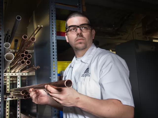 Person holding a copper pipe.