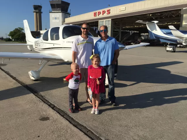 Two adults and two children standing in front of a plane.