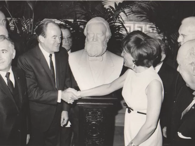 People standing around a bust.