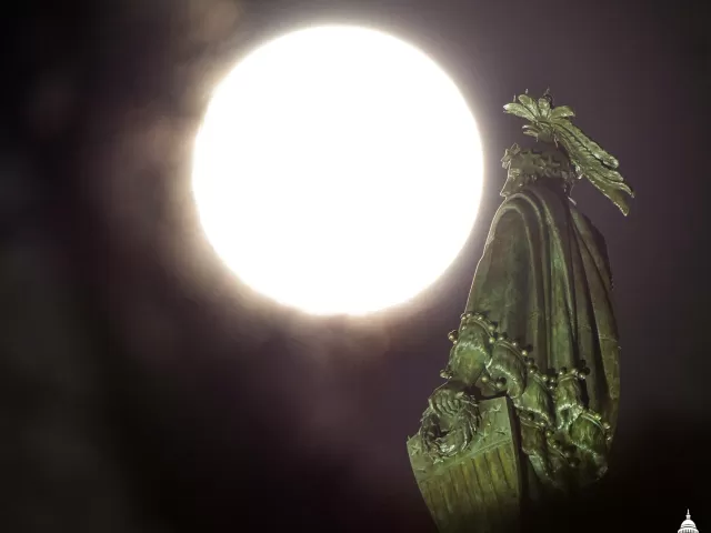 The moon and a statue of a person.
