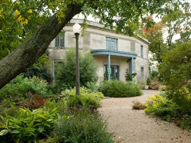 Building at the end of a tree lined path.