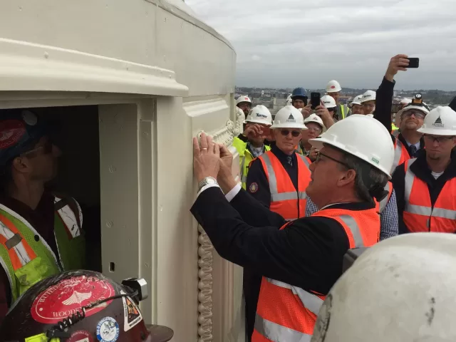 Group of people wearing safety vests and hard hats.